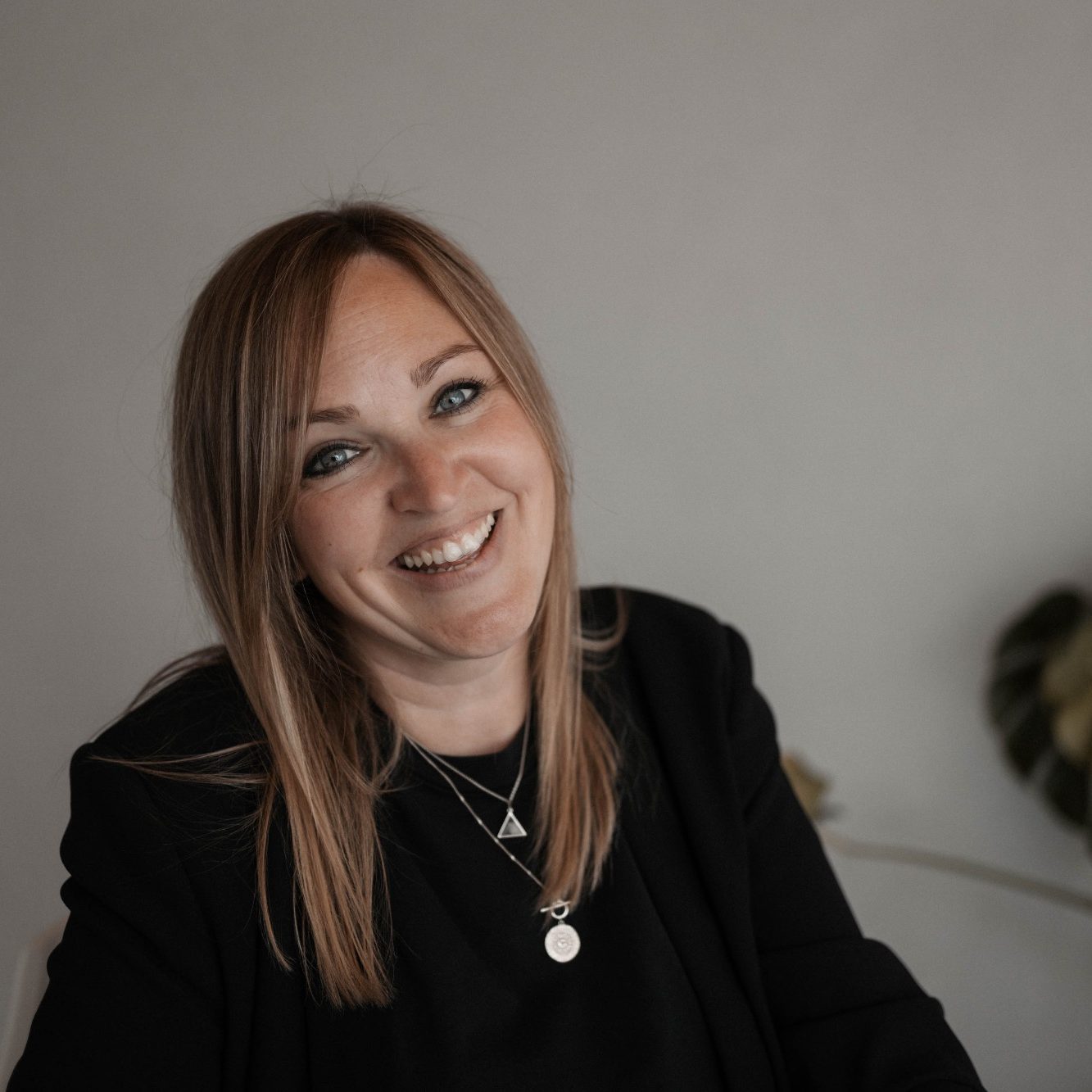 Sabine Welsch mit langen, braunen Haaren lächelt freundlich, trägt ein schwarzes Outfit.